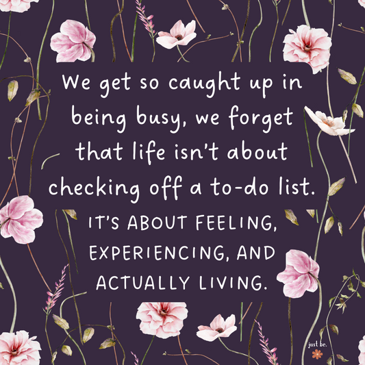Quote on a dark purple background with delicate pink flowers that says, "Life isn’t about checking off a to-do list. It’s about feeling, experiencing, and actually living."