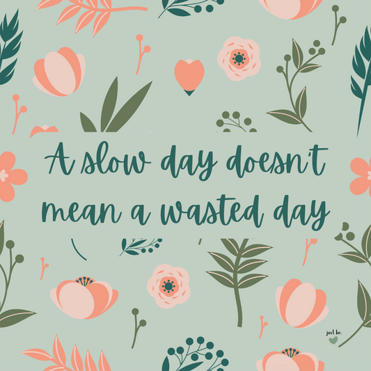 "A slow day doesn't mean a wasted day" on a soft green background with pink and coral flowers.