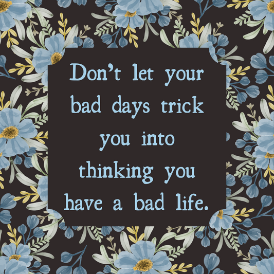 "Don’t let your bad days trick you into thinking you have a bad life." – an uplifting reminder on a floral background with blue flowers.