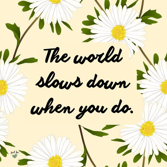 A soft yellow background with white daisies surrounding a quote that reads, "The world slows down when you do," reminding us to embrace a slower, more mindful pace.